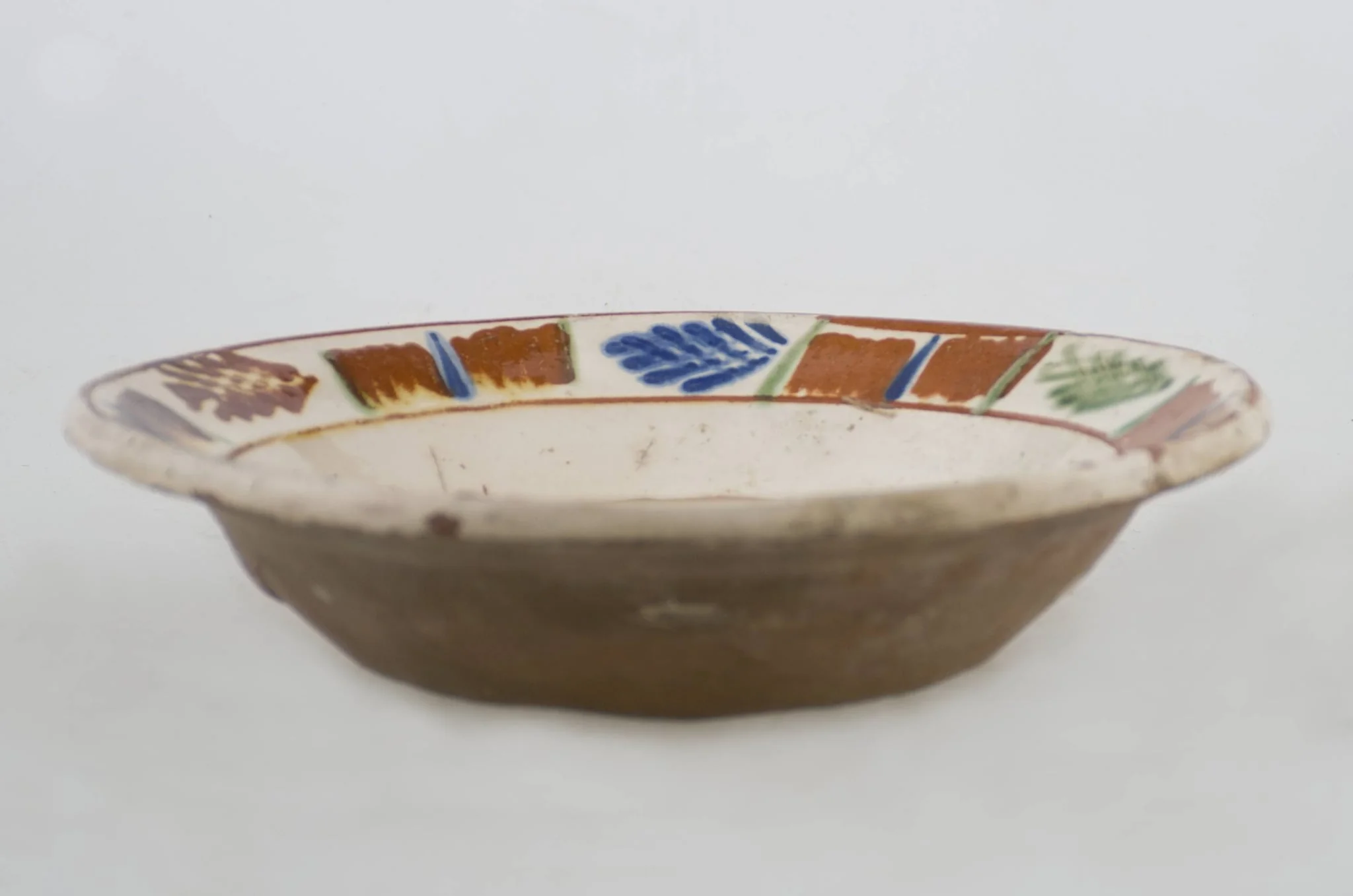 Vas ceramic de formă tronconică baza plată, pereții larg evazați și buza profilată. După modelarea la roată, uscarea și arderea recipientului, a fost aplicat un strat de angobă în interiorul vasului, peste care a fost pictat decorul floral și vegetal stilizat, format din două registre. În primul registru, situat pe fundul vasului și încadrat de o linie circulară, au fost realizate trei flori, cu petale albastre și mijlocul maro-roșcat, în jurul cărora se regăsesc petale verzi. Cel de-al doilea registru, cel care decorează buza vasului și este încadrat la rândul lui între două linii circulare, a fost decorat cu frunze și pete, despărțite de linii verticale. Cromatică: fond: alb; motive: maro-roșcat; albastru; verde., detail