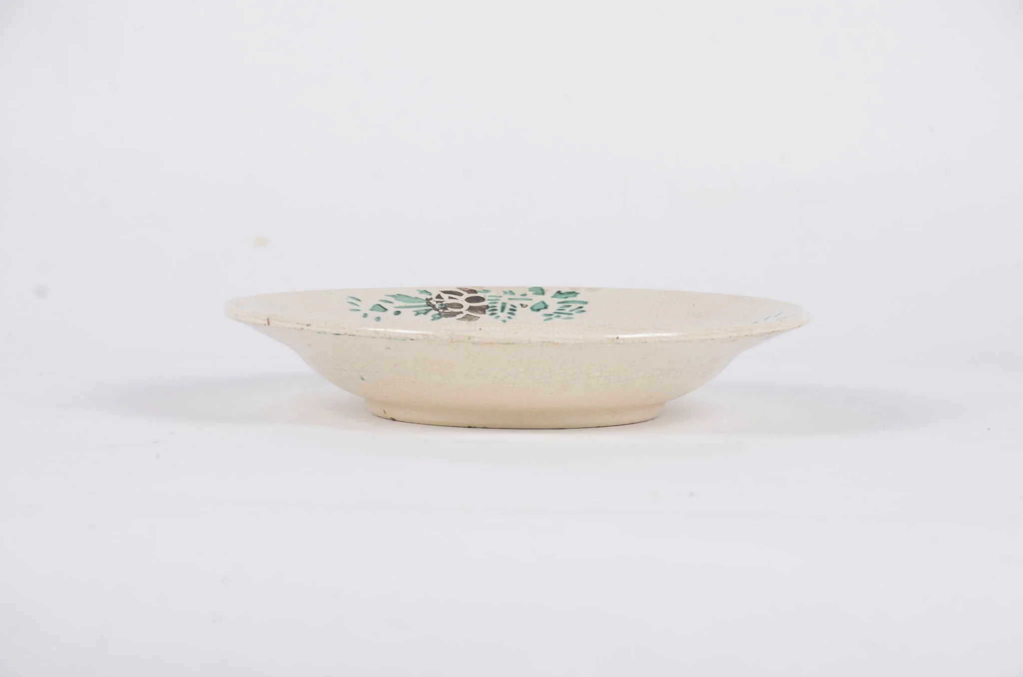 Farfuria este de formă tronconică fiind decorată cu motive florale dispuse central sub forma unui buchet de flori. Pe marginea piesei sunt dispuse într-un registru circular motive floral-vegetale pe un fond alb. Farfuria este smălțuită. Cromatică: fond: alb; motive: verde; maro., detail
