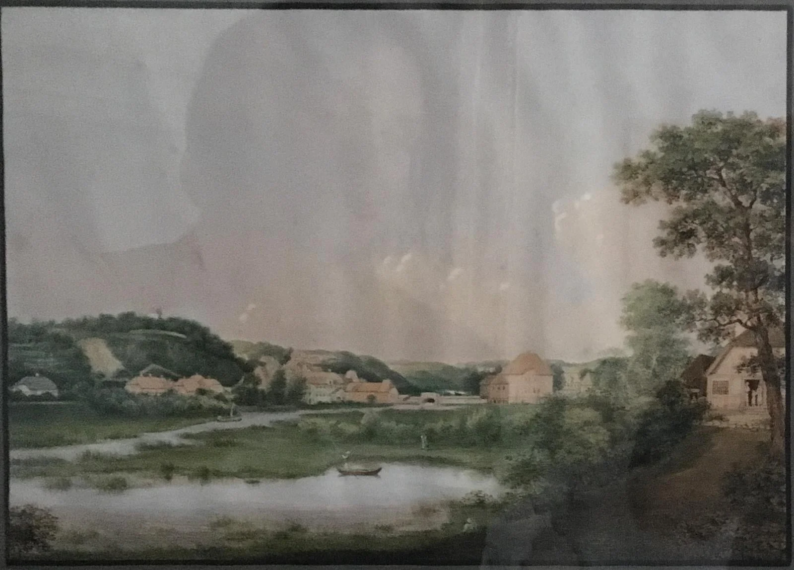 Parti fra Kiels omegn; ved åen der løber i skrå retning gennem billedet og udbreder sig noget mere i forgrunden ligger en lille landsby ved foden af en bakke, hvorigennem åen snor sig, detail