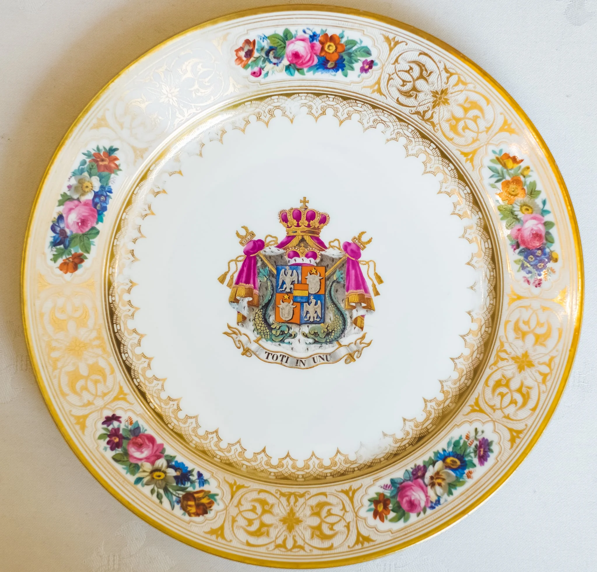 Farfurie, model decorativ stil Louis-Philippe, ales pentru serviciul de masa de peste 100 de piese Cuza, comandat la manufacturile regale din Sevres. Acesta urma să fie folosit de familia domnitoare Cuza în palatul de la Cotroceni. Farfuria este întinsă, circulară, pictată pe margini cu cinci medalioane florale care alternează cu arabescuri aurii. Este decorată central cu stema Principatelor Române și deviza unionistă „Toți în Unu". Stema și motivele florale se caracterizează printr-o vie policromie: galben, auriu, nuanțe de roșu, roz, verde și albastru. Pe reversul ei apar două marci în câmp circular: „Chateaux de Trianon" (culoare roșu carmin) și „Sevres 1846" (cu albastru). De asemenea, se remarcă cartelul care conține, în cifre latine, datele dublei alegeri a lui Al. I. Cuza ca principe al Moldovei și Țării Românești., detail