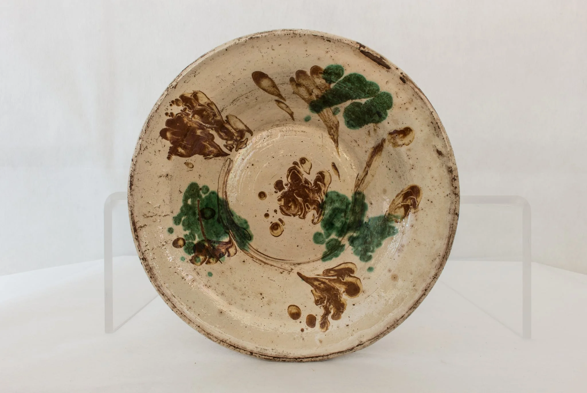 Vas de formă rotundă, adâncită, cu pereții evazați, smălțuit în interior, cu marginea ușor rotunjită, cu decor abstract realizat în tehnicile stropirii și scurgerii dirijate a colorantului maro. Cromatică: verde, maro, bej., detail