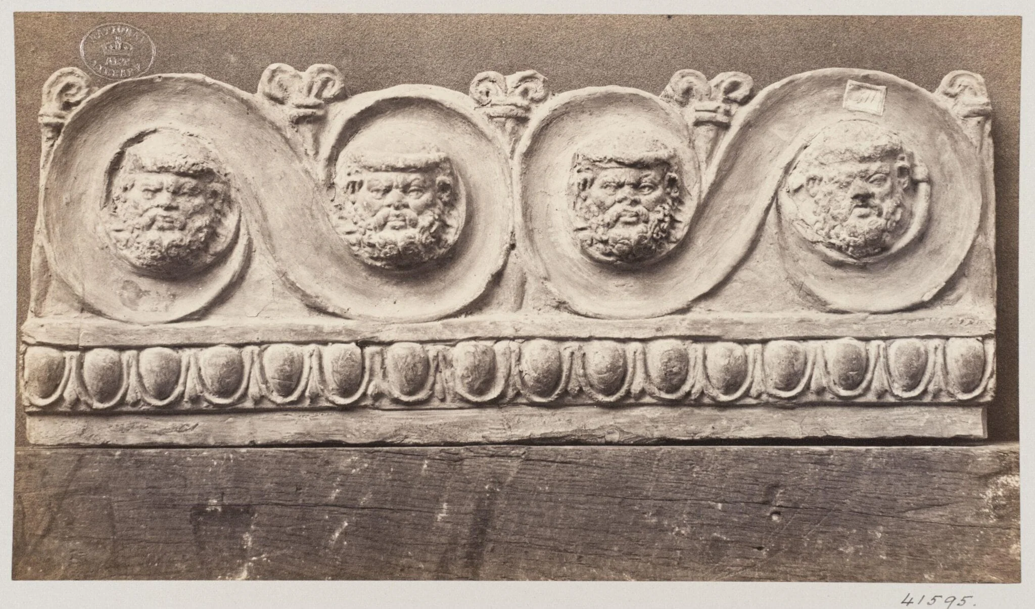 Bas-relief scroll with four masques in terra cotta, detail