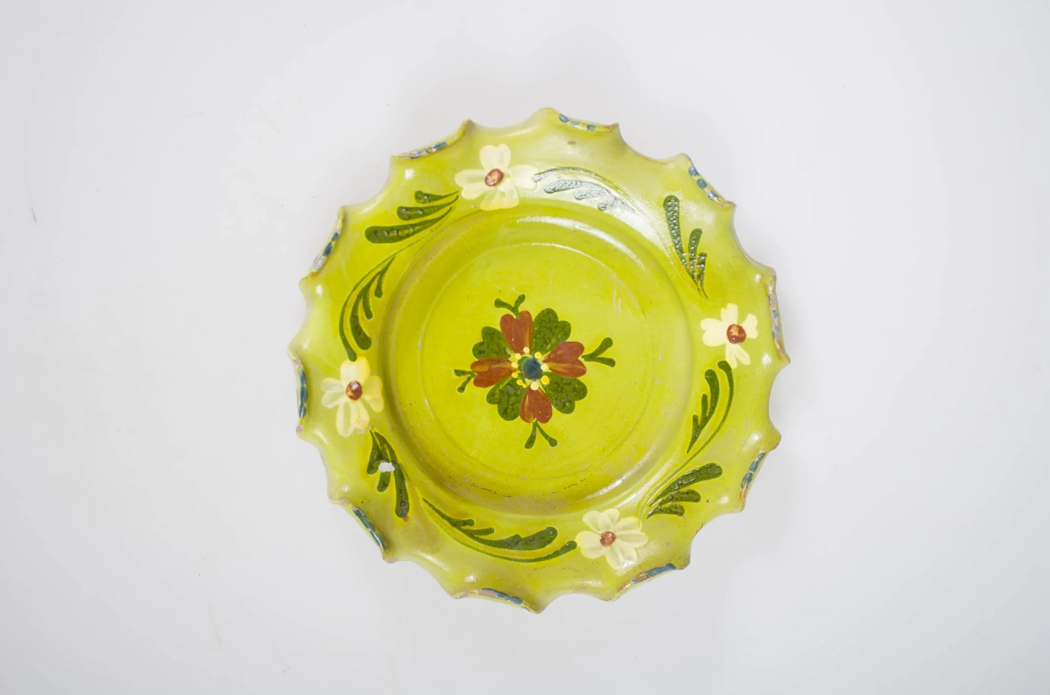Blid cu corpul de formă circulară, buza largă și ondulată. Decorul este plasat în două registre: central prezintă o floare; pe interiorul buzei un vrej cu patru flori. Cromatică: fond: galben; motive: verde închis; roșu; alb., detail