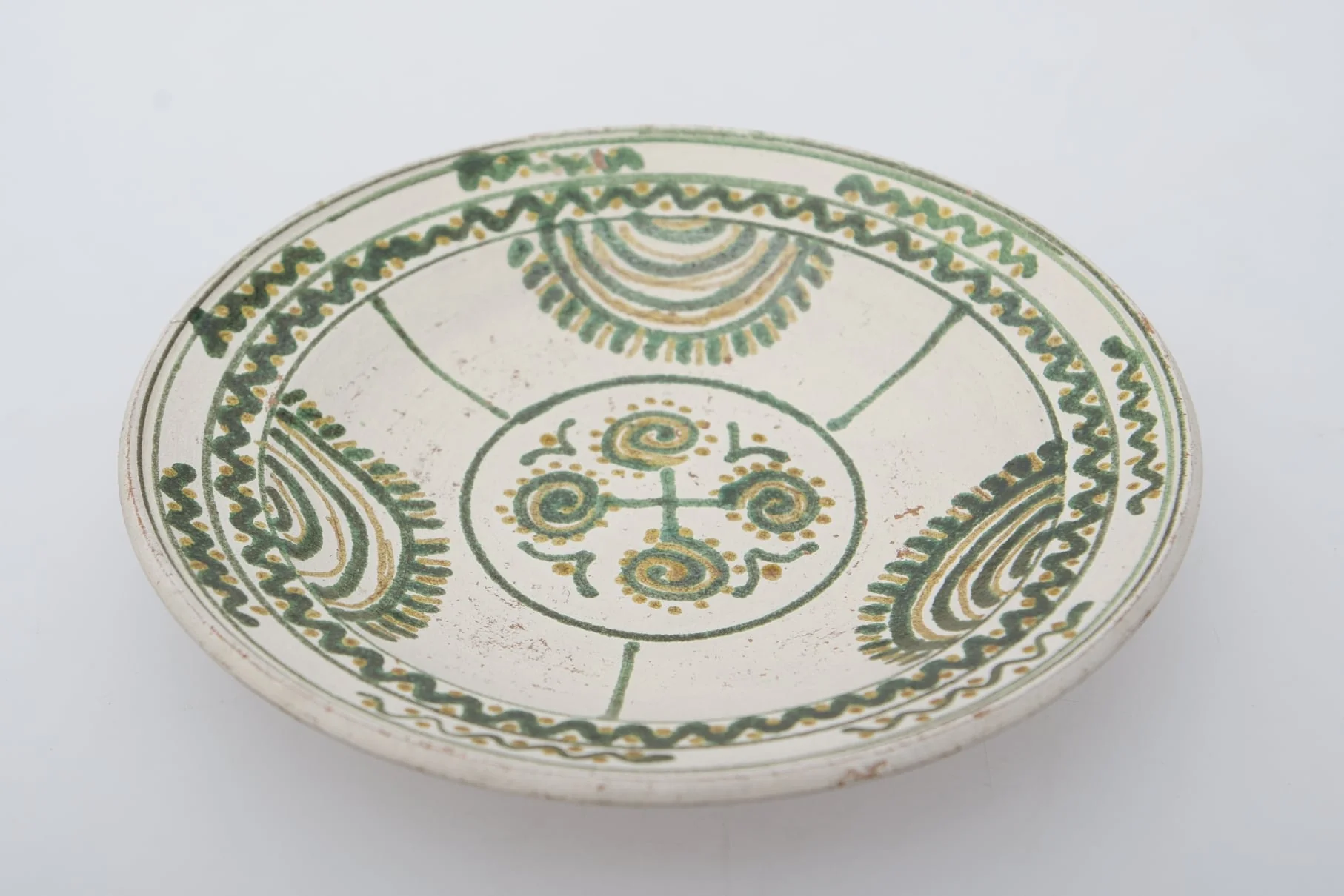 Vas ceramic de formă circulară și profil tronconic. Fața farfuriei a fost introdusă în angobă albă. Decorația a fost făcută cu pensula. Pe fundul farfuriei un cerc circumscris patru motive în spirală. Pereții farfuriei, au fost împărțiți în trei părți egale, pe circumferință, delimitate fiecare parte de o linie verticală, motivul bradului este reprezentat printr-o succesiune de semicercuri, pe ultima dintre ele pictându-se "țepii" bradului. Buza farfuriei a fost împărțită în două registre, în primul fiind pictat valul continuu, a doua cu val întrerupt. Pe fundul vasului, la spate, ștanțat ”D. Șchiopu C. Vlădești 1980'' înscris într-un cerc. Pe inelul de susținere dispuse două orifficii pentru atârnare. Cromatică: fond de angobă albă; motive: smalț verde și maro., detail