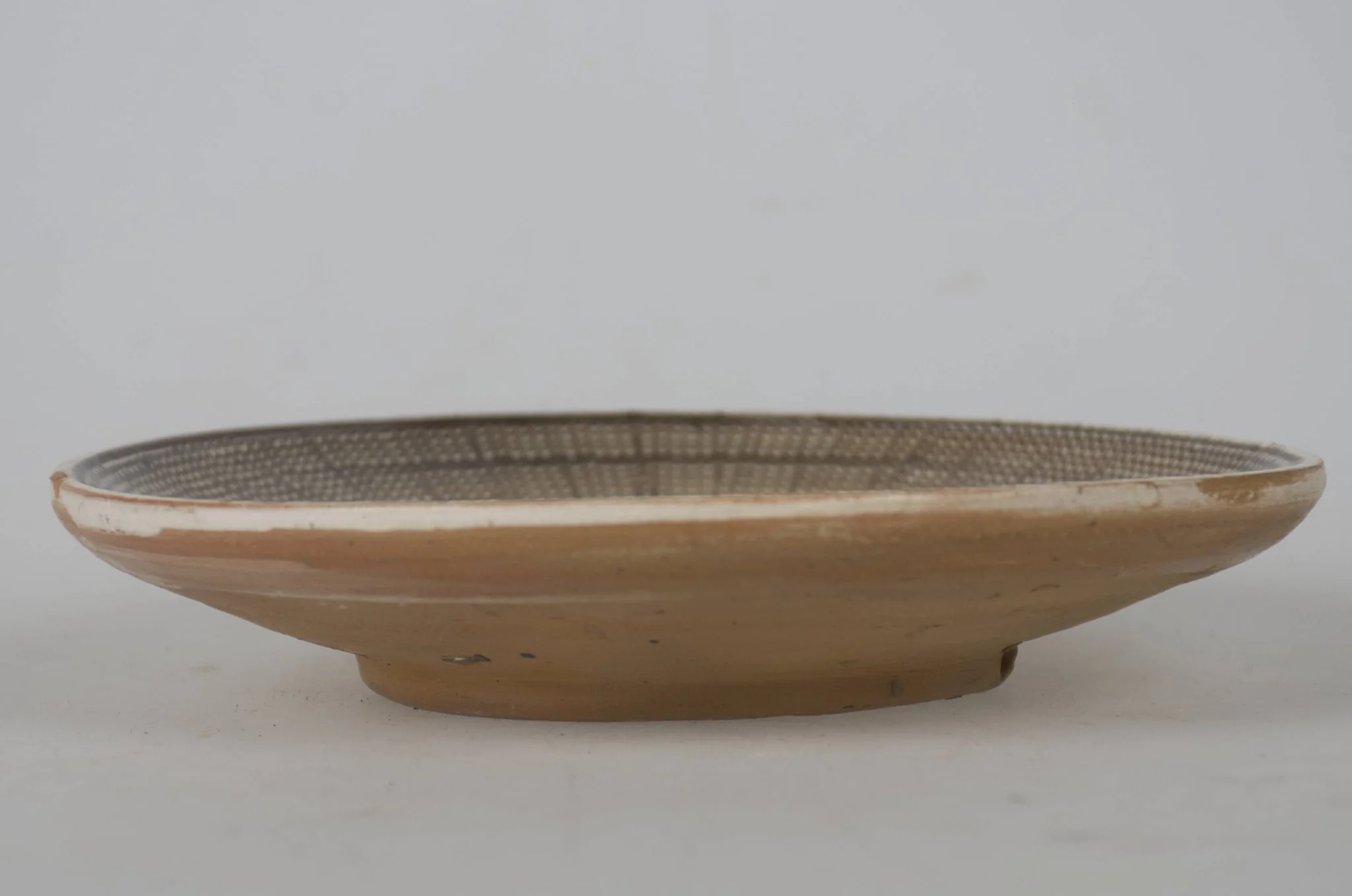 Vas ceramic smălțuit de mici dimensiuni, modelat la roata olarului, uscat, pictat, ars de două ori și smălțuit. Taierul prezintă o bază plată din care pornesc pereții foarte evazați/arcuiți cu buza ridicată. Decorul este dispus pe toată suprafața vasului, care în prealabil a fost angobat. Fundul vasului este nedecorat; în zona de demarcarea dintre fundul vasului și pereți un registru jirăvit, cuprins între două linii de culoare maro-roșcat. Un al doilea registru realizat din frunze de culoare verde, maro-roșcat și maro-închis. Marginea vasului a fost jirăvită, realizată cu „gaița”. Cromatica vasului este alb la interior și maro-deschis la exterior, iar cea a decorului pictat este maro-închis; verde; maro-roșcat; alb., detail