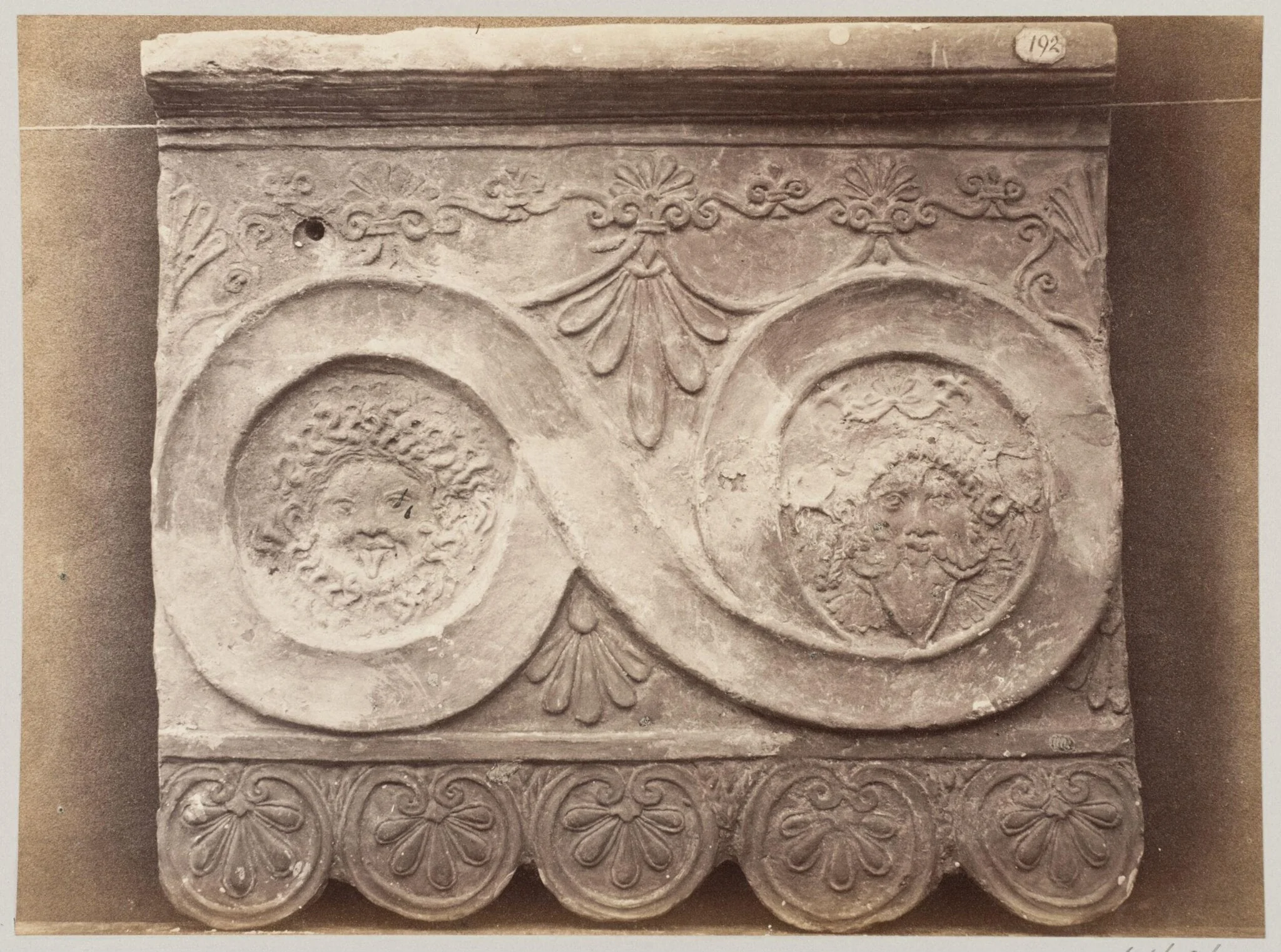 Bas-relief portion of a frieze of scrollwork with masks in terra cotta, detail