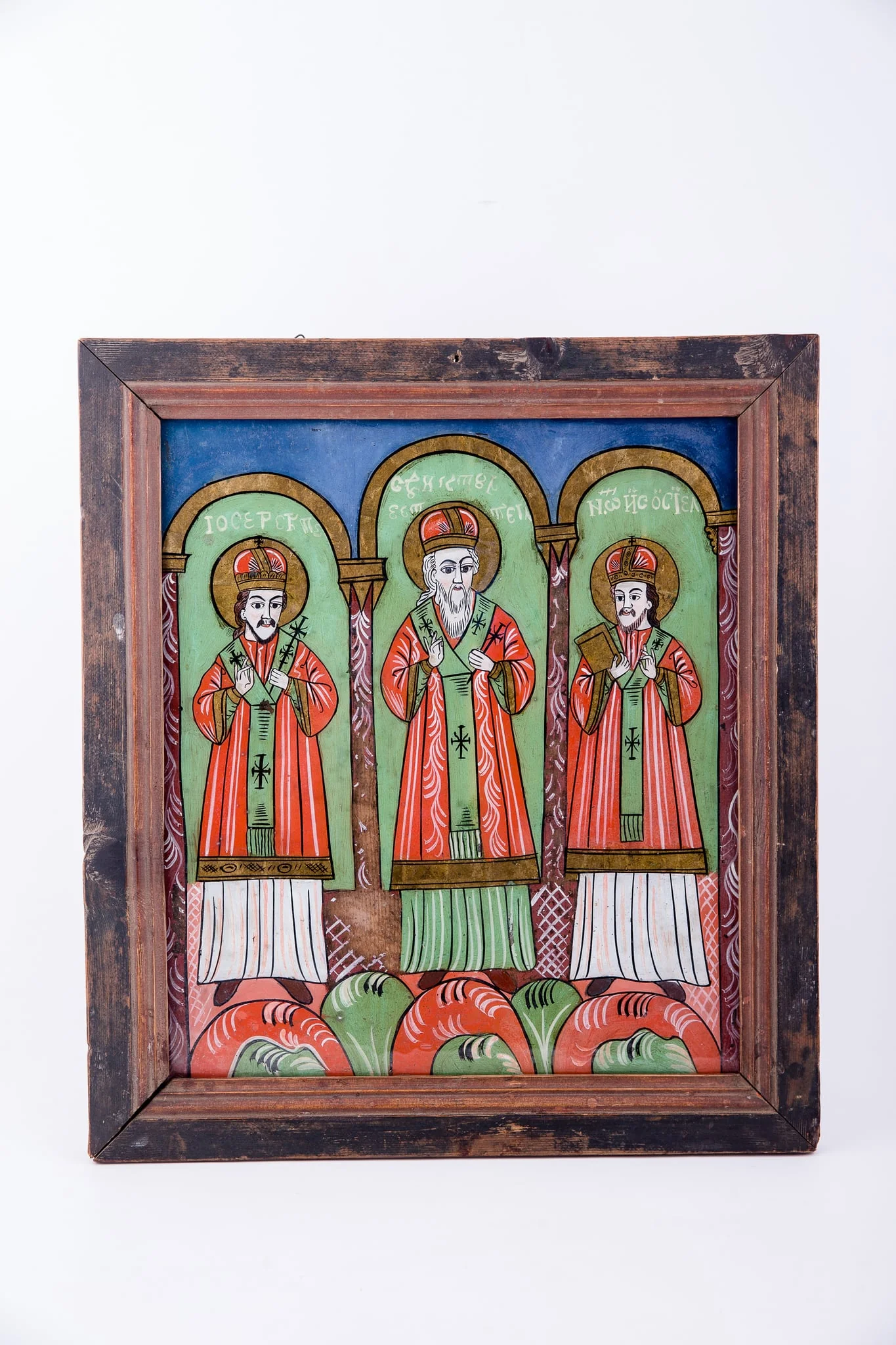 Cei Trei Sfinți Ierarhi Vasile cel Mare, Grigorie de Dumnezeu Cuvântătorul și Ioan Gură-de-Aur slujesc și săvârșesc Sfânta Liturghie împreună. Sunt înveșmântați în veșminte liturgice: sacos verde-alb-verde, felon roșu vermillon, epitrahil verde cu câte patru cruci. Sfântul Vasile cel Mare are Sfânta Evanghelie în mâna dreaptă. Sfântul Ierarh Grigorie de Dumnezeu Cuvântătorul Binecuvintează. Cei trei Sfinți Ierarhi stau cu picioarele pe perinițe rotunde de culori alternative: roșu, verde, alb. Fiecare sfânt ierarh este încadrat de două coloane și o boltă de biserică. Sunt prezente elemente arhitectură bisericească. Fondul registrului superior este albastru. Cromatica este luminoasă și armonioasă: verde, alb, roșu vermillon, roșu, albastru, negru. Este o icoană specifică picturii de Țara Făgărașului, cu un desen fin cu conturul negru și cromatica pastelată. După stilul picturii întregii compoziții, icoane poate să aparțină lui Matei Țimforea., detail