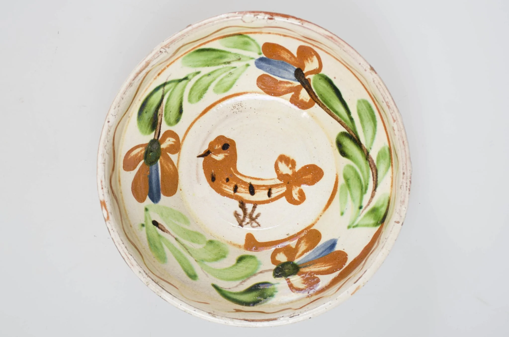 Blid de formă tronconică cu buza înaltă, smălțuit pe interior. Acesta este ornamentat cu motive florale, avimorfe, liniare și curbilinii, realizate prin pictare cu pensula. Pe buza interioară a vasului se identifică motivul geometric al liniei vălurite succedat de motive curbilinii care încadrează un registru floral-vegetal continuu dispus pe zona mediană a vasului. De asemenea, se identifică un motiv avimorf pictat pe fundul vasului și încadrat de un cerc. Obiectul este smălțuit la exterior doar pe buză, pe exteriorul buzei fiind incizate două linii. Fundul este inelar, prevăzut cu două orificii pentru agățare. Se identifică scurgeri insulare de smalț pe exteriorul buzei. Pe exterior se profilează, în zona diametrului maxim, un brâu continuu obținut prin lucrarea la roată. Cromatică: fond: alb (la interior); cărămiziu (exterior); motive: cărămiziu; verde; maro; albastru., detail