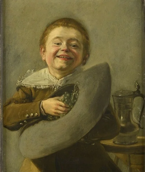 Smiling boy holding grapes in his hat, detail