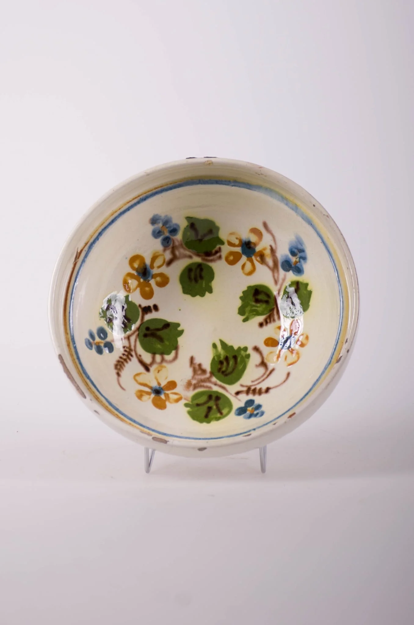 Farfurie de formă tronconică, adâncită, cu buza foarte înaltă; pe fund are găuri pentru agățare. Este smălțuit în interior și exterior (buza). Decorat cu motive geometrice: linie; motive fitomorfe; motive florale. Cromatică: fond: alb; motive: verde; maro; albastru., detail
