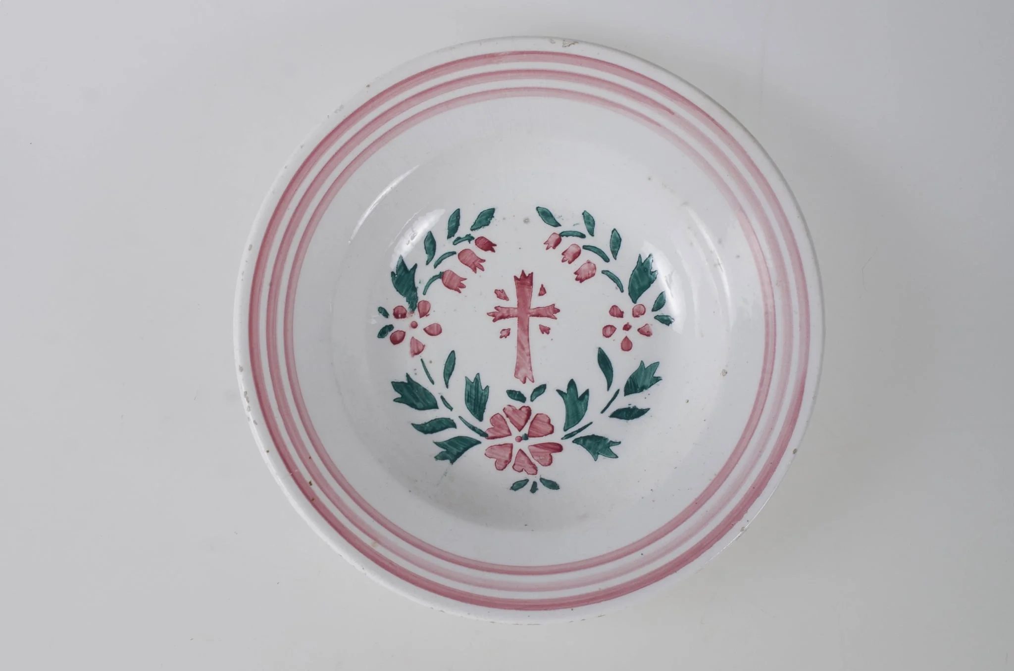 Farfurie de formă tronconică, adâncită; pe margine este decorată cu motive geometrice: trei cercuri concentrice. În centru este pictată o cruce, încadrată de flori și frunze dispuse circular. Pe exteriorul vasului de la bază spre buză se disting trei profile circulare. Cromatică: fond alb; motive: roșu; verde., detail