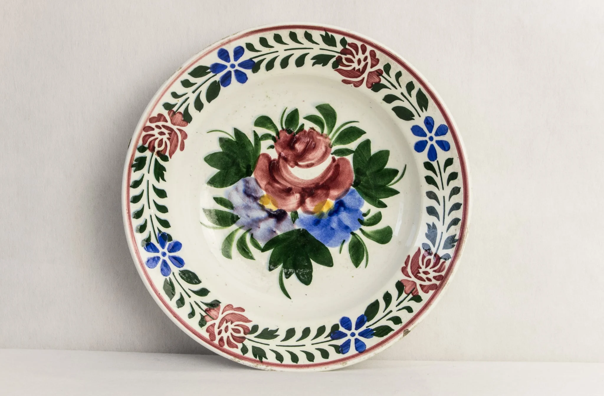 Vas de formă rotundă, smălțuit în interior și exterior, decorat pe suprafața interioară prin pictare manuală astfel: central, un motiv floral reprezentând buchetul cu flori; pe margine, motive florale dispuse circular (trandafiri și albăstrele). Pe fundul vasului este prezentă marca manufacturii din Hollóháza (inscripția Magyar. Gyártmányi 10 și casa cu corb). Cromatică: alb, albastru, verde, galben, roșu., detail