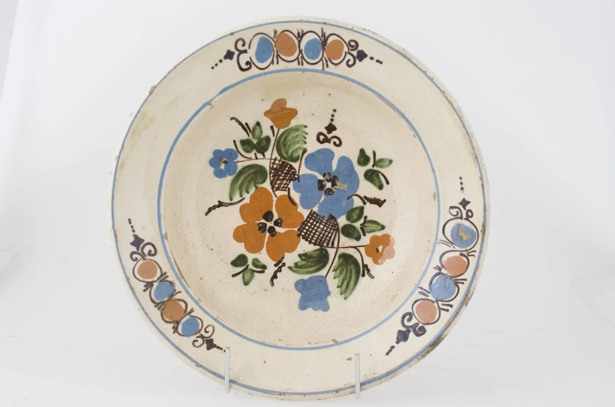 Farfuria este lucrată la roată, prezintă marginea evazată în plan orizontal fiind smălțuit în interior. Pe suprafața interioară a vasului se identifică registre decorative floral-vegetale dispuse pe fundul vasului și pe marginea interioară. Registrele sunt delimitate de două cercuri realizate prin pictare și dispuse pe buza vasului și spre interiorul acestuia. Cromatică: fond: alb; motive: roșu; albastru; verde; brun; maro., detail