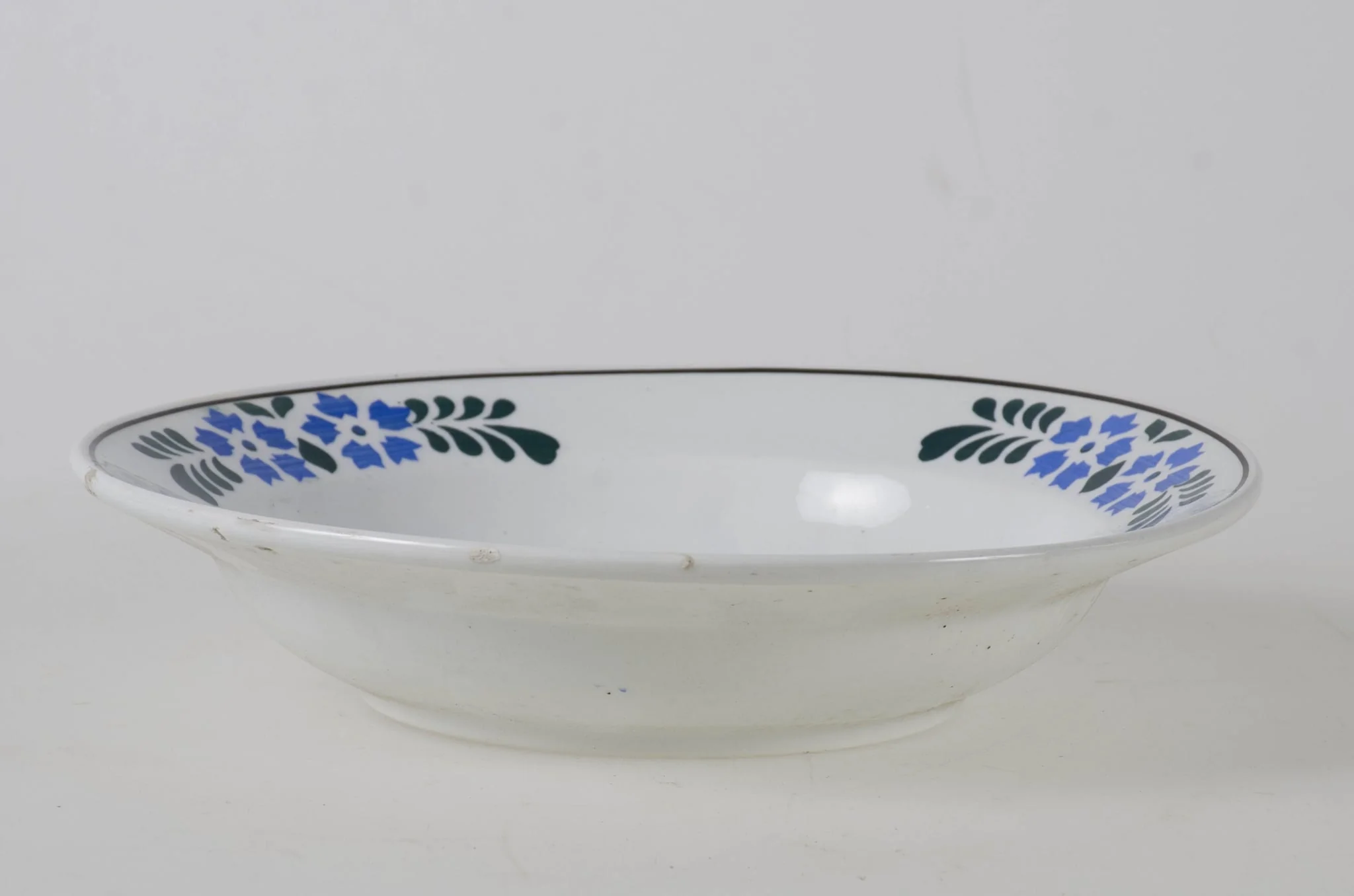 Vasul are formă tronconică smălțuit la interior și pe exterior (smalț de culoare albă). Prezintă motive decorative floral/vegetal și geometrice dispuse pe fundul vasului dar și într-un registru decorativ dispus pe buza vasului. De asemenea se identifică și motive decorative geometrice: pătratul, cercul, linia. Cromatică: fundal alb; verde; grena; albastru., detail