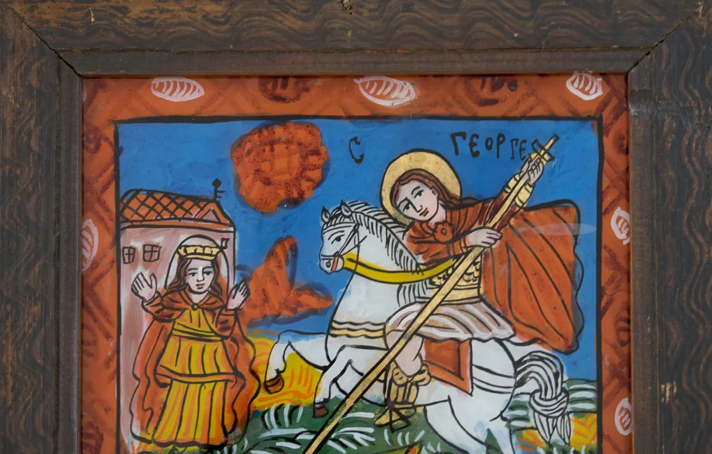 Icoana îl reprezintă pe sfântul Gheorghe omorând balaurul, în varianta mai elaborată, în care apare și fata de împărat și elemente etnografice locale. Sfântul, călare pe cal alb, plasat central. Veșmintele sunt asemănătoare celor ale soldaților chezaro-crăiești, cizme înalte, tunică scurtă, zale, mantie roșie fluturând în vânt. Are capul descoperit, plete lungi, castanii, ochi mari, gura roșie, trăsăturile bine definite, expresive. În mână ține o suliță lungă, cruciformormă,aurită, cu care omoară balaurul înaripat, căzut la pământ, scoțînd limbi ascuțite. Calul este alb, capul mic, coada înnodată. Relieful este realizat prin linii albe) și vrâste de culoare(verde, galben,roșu), marcate cu motive fitomorfe. Câmp albastru închis, înviorat de o floare roșie. În partea stângă, în plan îndepărtat, în fața palatului sugerat printr-o clădire simplă,albă, înaltă, cu acoperiș de olane roșii, se află fata de împărat pe care o salvează sfântul conform legendei. Întreaga compoziție este încadrată de un chenar rectangular de culoare roșie, decorat cu o spirală de nuanță asemănătoare și mici ovale hașurate cu alb. Desenul complicat, tușa groasă, culorile intense, asemănător vitraliilor. Umplerea cu culoare neglijentă indică o producție de serie. Rama din lemn de brad, cafeniu închis, decorată unda apei. Dosul este realizat din două scândurele de brad dispuse orizontal., by anonim