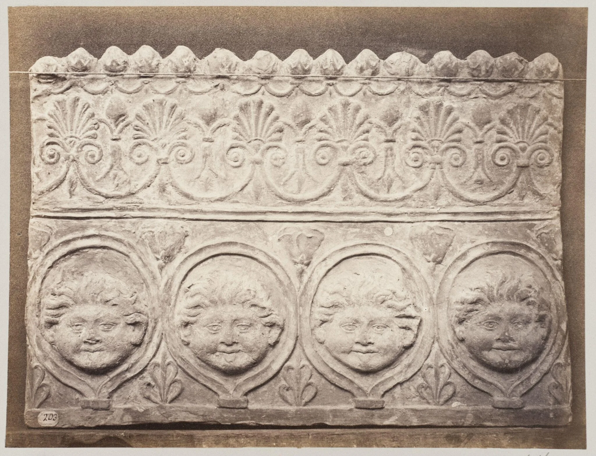 Bas-relief portion of a frieze of four masked young satyrs in terra cotta, detail