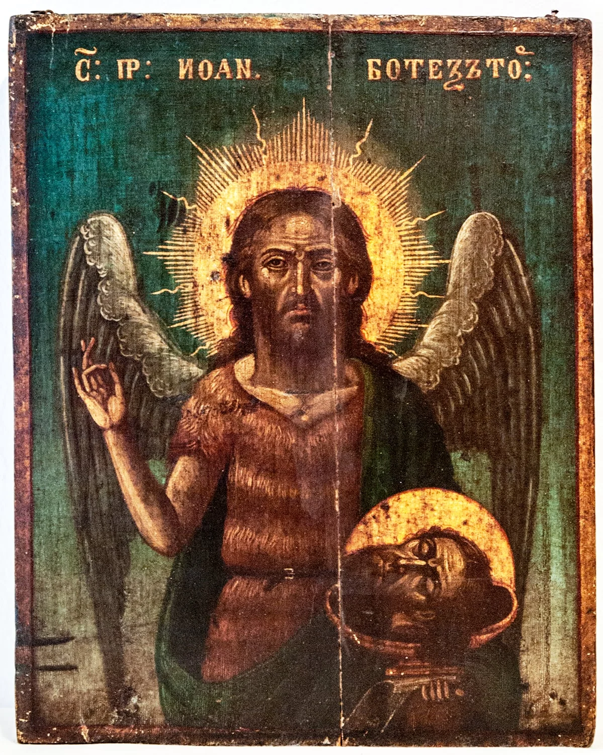 Icoana îl redă pe Sfântul Ioan Botezătorul 3/4, în ipostaza de Înger al Pustiului, cu aripile strânse, ținând propriul cap tăiat pe o tipsie. Este înveșmântat conform canoanelor, cu blana de cămilă încinsă la mijloc, pe umărul drept având prinsă o mantie verde. Chipul este sobru, încruntat, carnația întunecată, trăsăturile severe, părul ușor în neorânduioală, în jurul capului aureolă din raze. Cu dreapta binecuvintează. Fondul verde smarald, inscripția cu litere aurii dublate cu roșu, majuscule. Pictura studiată, tehnica evoluată. Colț dreapta jos semnătura F(sau T). Marinescu, dreapta anul 1887. Capul de pe tipsie, are aureolă. Chenar dublu, linie subțire roșie, bandă aurie. Lanțișor complex pentru atârnat pe perete., detail