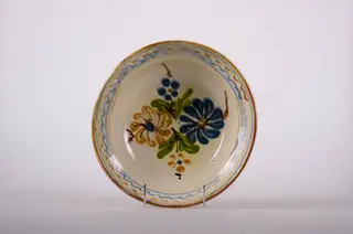 Blid de formă tronconică, adâncit; pe fund are găuri pentru agățare. Este smălțuit în interior și exterior (buza); este decorat cu motive geometrice: linie, linie ondulată; motive fitomorfe: frunze; motive florale. Cromatică: fond: alb; motive: albastru; maro; verde.