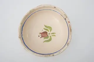 Blid de formă tronconică, adâncită; este smălțuit interior și exterior (doar buza); este decorat cu motive geometrice pe margine: linie; în centru este decorat cu motive florale: lalea. Cromatică: fond crem, maro, verde, albastru., 1850