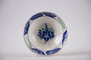 Blid de formă tronconică cu buza evazată, Smălțuit la interior. Decorul este format din ornamente florale dispuse pe motiv central: floare; motive marginale, fitomorfe: brăduț. Cromatică: verde și albastru pe fond alb., 1850