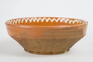 Blidul adânc are formă tronconică, cu buza îngroșată și ușor răsfrântă. Acesta este modelat la roată, ars, smălțuit (pe interior) și ornamentat cu motive florale și geometrice (liniare și oblice) dispuse după cum urmează: motivele floral vegetale dispuse într-un registru în zona mediană a vasului; pe fundul vasului, în interior, se identifică de asemenea motive floral vegetale încadrate într-un cerc. Pe zona diametrului maxim se identifică motivul liniei vălurite urmată de un cerc obținut prin pictare. Vasul are buza înaltă fiind nesmălțuit și neornamentat la exterior. Acesta este smălțuit la exterior doar pe buză. Prezintă scurgeri de smalț pe exteriorul buzei. Blidul este prevăzut cu două orificii pe fundul vasului, pentru agățare. Cromatică: fond: cărămiziu; motive: alb; verde., 1850
