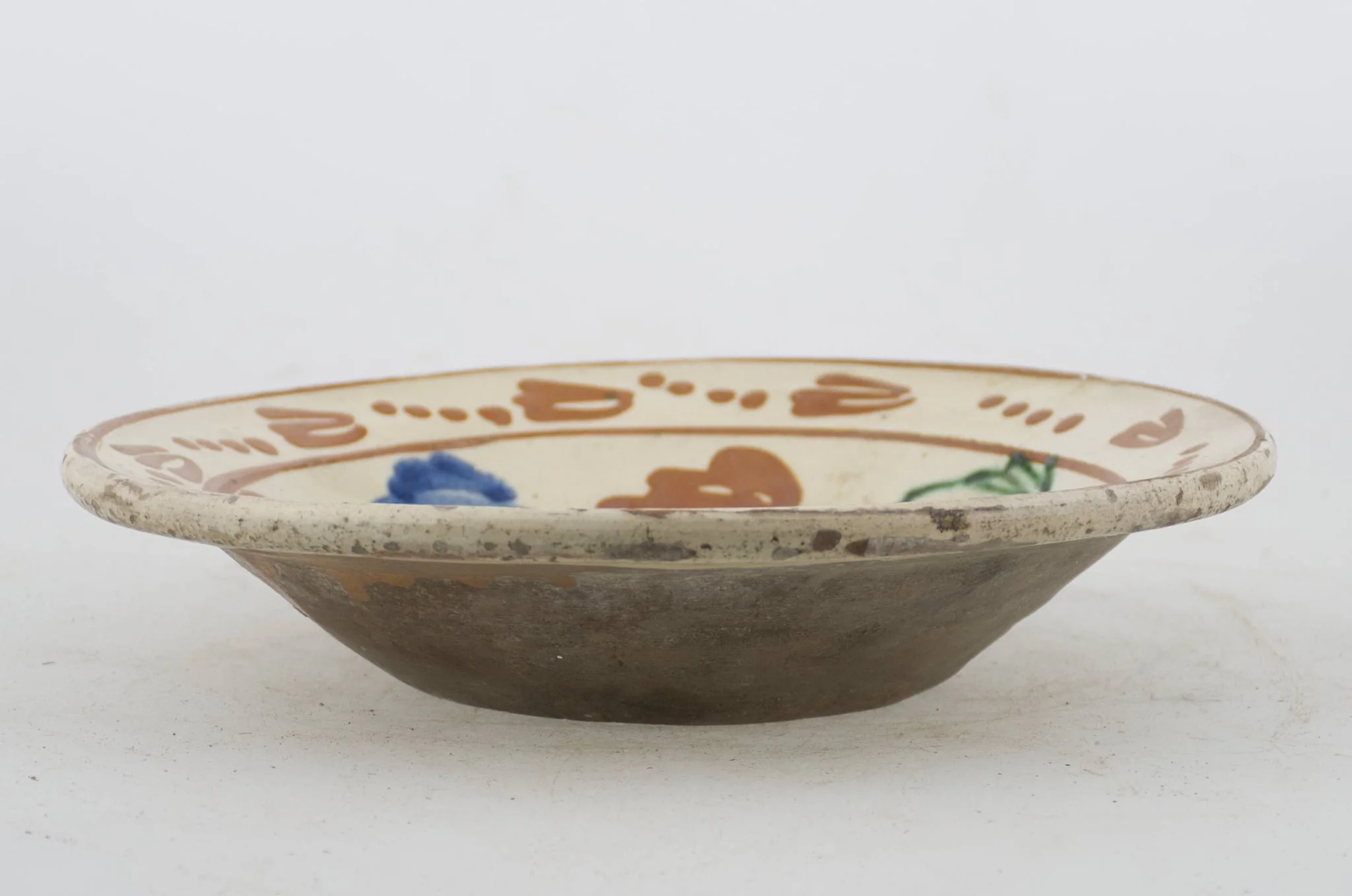Vas ceramic de formă tronconică cu baza plată, pereții larg evazați și buza profilată. După modelarea la roată, uscarea și arderea recipientului, a fost aplicat un strat de angobă în interiorul vasului, peste care a fost pictat decorul floral și vegetal stilizat, format din două registre. Primul registru, situat pe fundul și pereții vasului, și încadrat de o linie circulară, a fost decorat cu motive florale stilizate: pe fundul vasului se află o floare, cu petalele de diferite culori. Pereții recipientului ceramic au fost decorați la rândul lor cu opt flori, dispuse concentric. Al doilea registru, cel care decorează buza recipientului ceramic, și este mărginit la rândul lui de o linie circulară, prezintă un brâu compus din nouă flori cu tulpinile formate din patru puncte. Cromatică: alb la interior; cărămiziu la exterior; motive: albastru; verde; maro-roșcat., detail