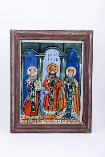Cei Sfinți Trei Ierarhi Vasile cel Mare, Grigorie de Dumnezeu Cuvântătorul și Ioan Gură-de-Aur slujesc și săvârșesc Sfânta Liturghie împreună. Sunt înveșmântați în veșminte liturgice: sacos, felon și epitrahil mithră și aureolă. Cromatica veșmintelor este vie și luminoasă: roșu vermillon, orange-cărămiziu, galben-ocru și albastru ceruleum și bleu-ciel, verde și alb. Sfântul Vasile cel Mare are crucea în mâna dreaptă și binecuvântează și în mâna stângă ține Sfânta Evanghelie închisă. Sfântul Ioan Gură-de-Aur, central, tânăr cu barba brunetă, binecuvântează cu ambele mâini și are pe bedernița romboidală un chip de sfânt, element antrpomorf. Alături este Sfântul Grigorie care ține în mâna stângă cârja-sceptrul arhiepiscopală și binecuvântează. Fondul întregii tematici iconografice este albastru ceruleum în exterior și central bleu-ciel. Sfinții trei ierarhi sunt încadrați de coloane și arcade-bolți, schițându-se astfel structura arhitecturală de biserică. În registrul inferior este un un caroiaj alb-ocru, o lespede de fundație puternică - reprezentând credința creștin-ortodoxă. Cromatica este luminoasă și armonioasă: roșu vermillon, orange, verde spanac-avocado, galben-ocru, brun, albastru ceruleum și bleu-ciel, gri, alb și negru. Este o icoană de Valea Sebeșului. Inscripiția din româno-chirilică se traduce: Sfântul Vasilie Sfântul Ioan Sfântul Grigorie. Icoana este datată 1908.