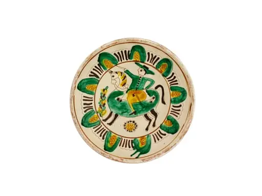 Strachină lucrată în manieră Kuty, de formă tronconică, modelată la roată; decor geometrizat și naturalist amplasat pe toată suprafața vasului organizat în două registre despărțite de linii circulare realizate cu cornul: central prezintă un motiv antropomorf: călăreț cu sabia în mână încălecat pe cal și motive fitomorfe: floarea soarelui și brăduț; spre marginea vasului un registru cu motive geometrice semiovoidale realizate cu linii curbe și hașuri, despărțite de grupuri de liniuțe; cromatică: fond alb dat de angobă, decor realizat cu verde, galben, brun și cărămiziu. Pe exterior este imprimată ștampila cu numele meșterului scris cu majusculă și caractere italice: Colibaba.