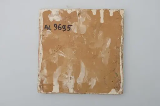 Piesă ceramică de formă pătrată, smălțuită și angobată, laturile pătratului fiind marcate de două chenare, primul vălurit, al doilea în linie dreaptă. Ornamentată cu motive zoomorfe și floral-vegetale, după fabula lui La Fontaine, Vulpea și barza: o vulpe care bea dintr-un ulcior și o barză care mânâncă dintr-un vas plat aflat pe o măsuță joasă. Pe două din colțuri, două flori completează pictura. Motivele au fost la început incizate, iar apoi pictate. Pe spate, cahla este prevăzută cu un orificiu pentru prinderea aței. Tot aici, este inscripționat numele meșterului olar, "Colibaba". Cromatică: fundal alb; motive: verde, galben, maro, cărămiziu., by Colibaba Marcel