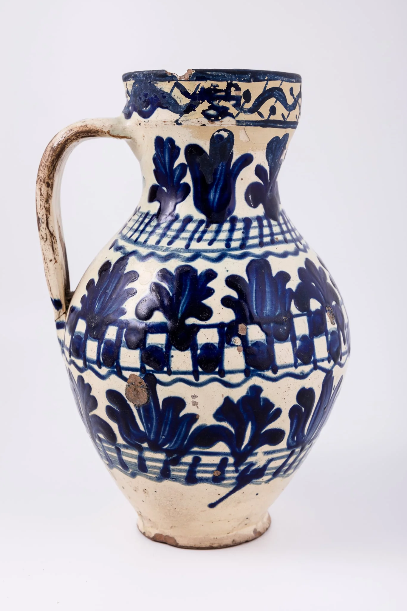 Cană piriformă prevăzută cu o toartă dreaptă și lată, gura rotundă. Suprafața decorativă a vasului este împărțită în șapte registre decorative: cel din partea superioară, pe buza vasului este dispus orizontal, iar celelalte șase, dispuse vertical. Primul registru, așezat pe marginea dreaptă a cănii redă o linie vălurită intercalată de puncte. Registrul al doilea, al patrulea și al șaselea prezintă motive fitomorfe și florale, brăduți intercalați de lalele înflorite stilizate. Registrul al treilea, dispus pe gâtul cănii și al șaptelea, dispus la bază, prezintă linii circulare orizontale intersectate de linii verticale. Registrul al patrulea prezintă tabla de șah. Toarta este pictată cu pensula. Cromatica: alb, albastru-cobalt., detail