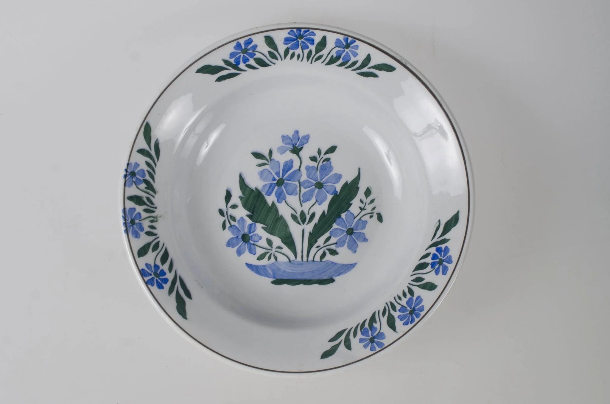 Vasul are formă tronconică, adâncită și este decorat cu motive florale dispuse în trei registre a câte trei flori pe margine, încadrate de o linie; în centru este decorat cu flori și frunze. Pe fund are trei cercuri concentrice care profilează trei registre. Vas evazat în partea superioară. Smălțuit interior-exterior. Cromatică: fond: alb; motive: verde; albastru; negru., detail