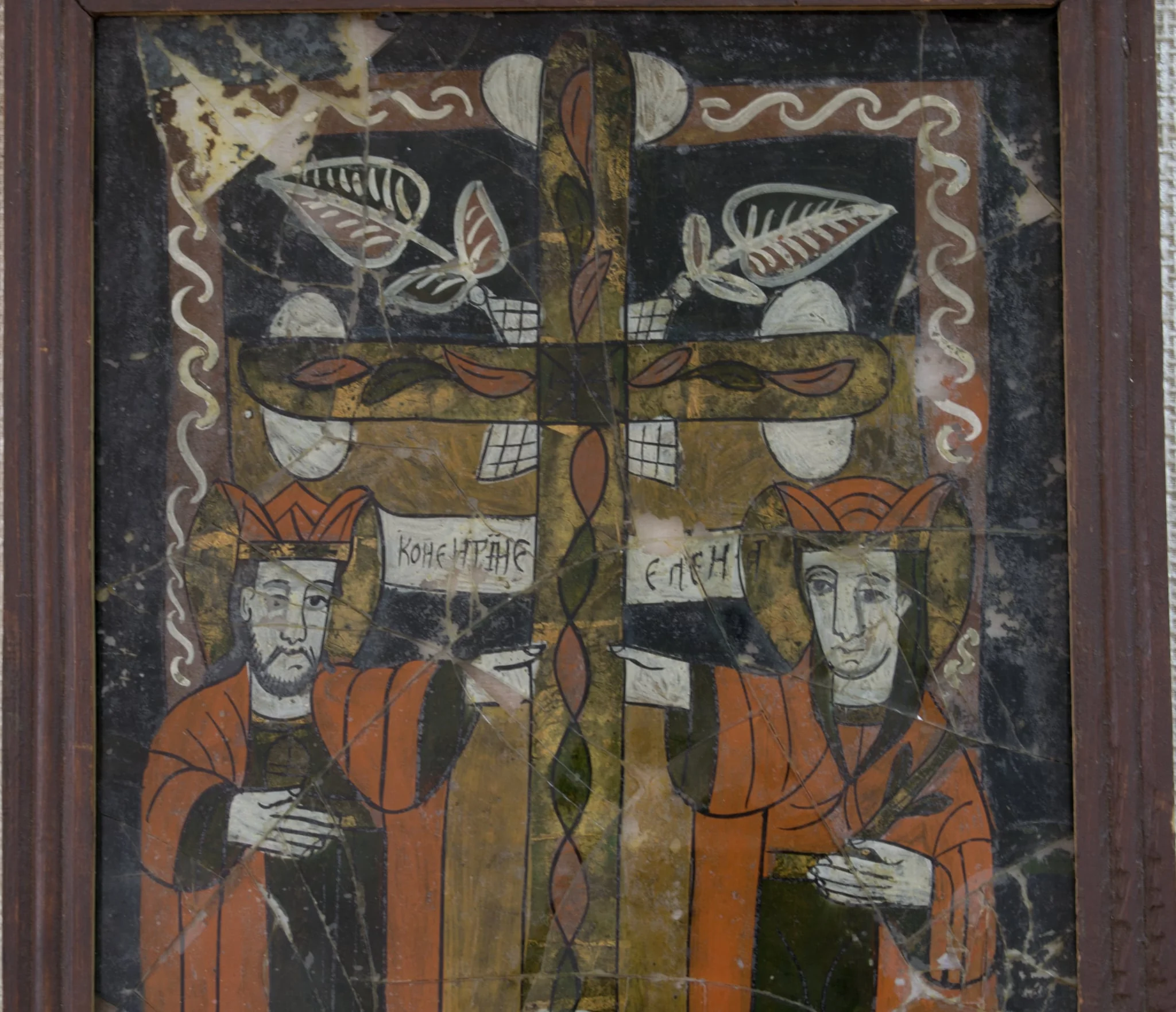 Pictură în oglindă, pe spatele unei bucăți de glajă, ax vertical.Sfinții Împărați Constantin și Elena, 3/4 , în picioare, semiprofil, sub brațele crucii pe care a fost răstignit Isus( găsită de Împărăteasa Elena la Ierusalim) Amândoi au plete castanii, lăsate pe umeri, coroane înalte, veșminte identice, simple, lungi, cămăși verzi și mantii roșii. Plasarea personajelor sub brațele crucii, în jumătatea inferioară, pe fond ocru sugerează complementaritatea celor două planuri(terestru și ceresc). Împărăteasa ține în mână o ramură verde, element ce o însoțește în majoritatea reprezentărilor populare. Fețele sunt ușor diforme, ochii negri. Crucea dreaptă, plasată în centrul compoziției, decorată cu frunze și o spirală în partea de jos, creează simetrie. La întretăierea brațelor crucii elemente vegetale cu contur alb. Chenarul specific icoanelor de Nicula, linia albă(zăluțe, funie) pe fond roșcat. Icoana este caracteristică perioadei de înflorire a picturi pe sticlă de la Nicula. Rama profilată, din lemn de brad, pictată cu o culoare roșcată. Dosul subțire. Sticla spartă în mai multe fragmente., detail