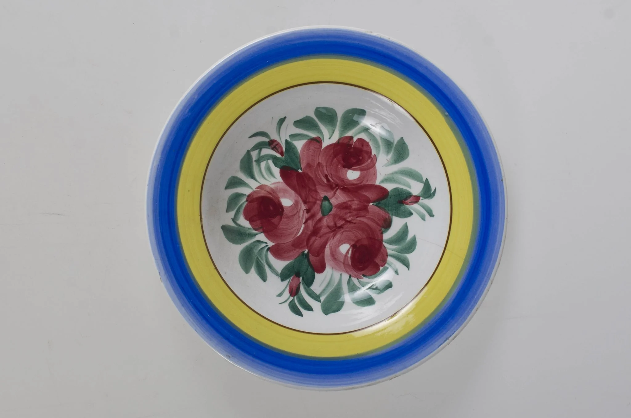 Farfurie de formă tronconică, adâncită; motive florale în centru (trandafiri); pe margine este decorat cu trei cercuri concentrice. Pe fund este o ștanță: o casă cu o pasăre pe acoperiș cu inscripție deasupra: ”MAGYAR” și dedesubt: ”1971” și un cuvânt indescifrabil. Pe fundul vasului sunt două incizii în care este introdus un șnur folosit la agățarea vasului pe perete. Vasul este smălțuit interior-exterior. Decor obținut prin pictare. Cromatică: fond: alb, motive: roșu; verde; albastru; galben., detail