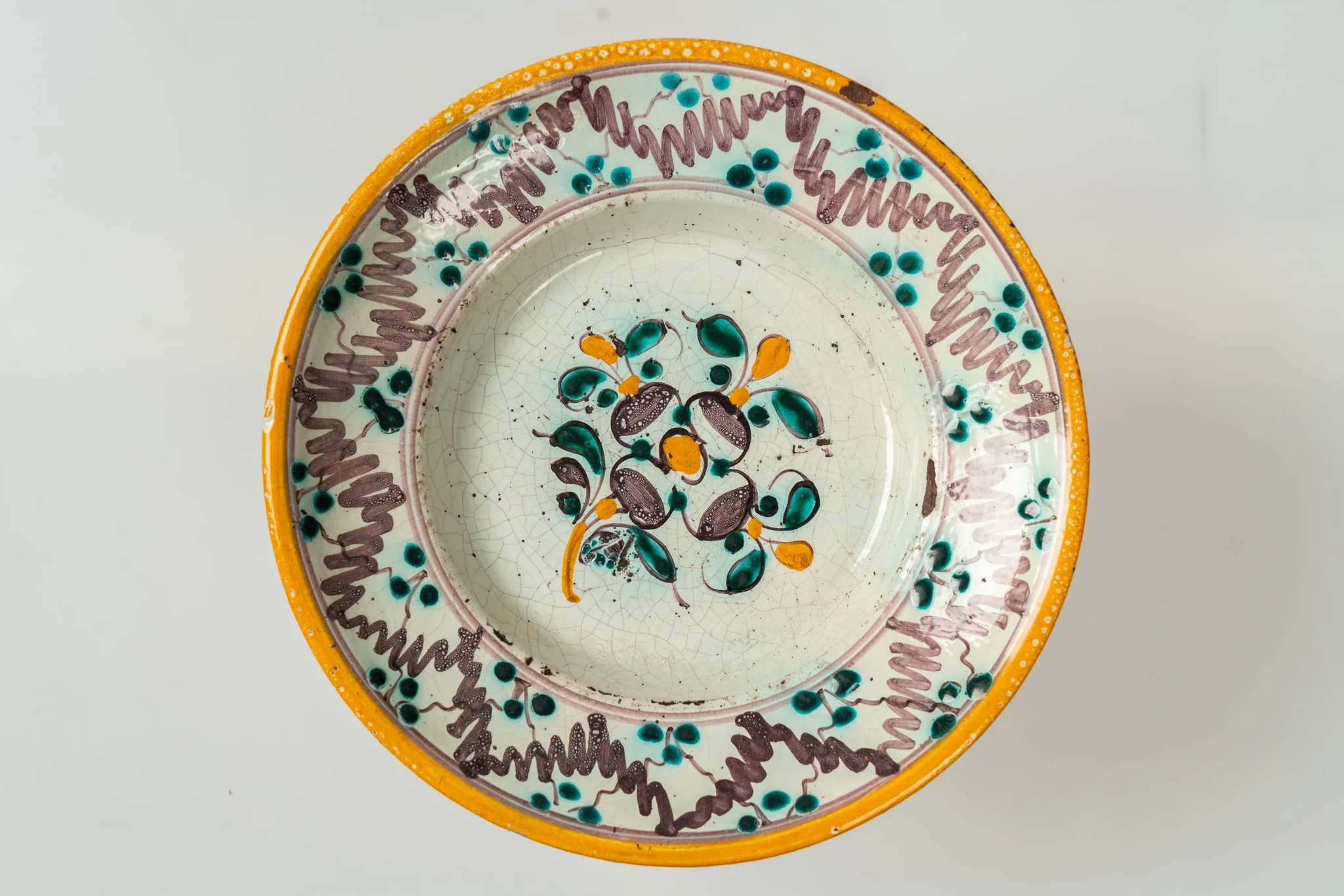 Farfurie de formă semi-adâncă, cu buza lată, răsfrântă. Decorul, dispus pe un fond alb, prin pictare, este format din motive florale fin stilizate (flori și frunze), dispuse central, pe fundul farfuriei, și motive geometrice pe buza acesteia (linii vălurite, puncte, cercuri concentrice). Cromatica decorului: alb, verde-turcoaz, brun, galben-ocru., detail