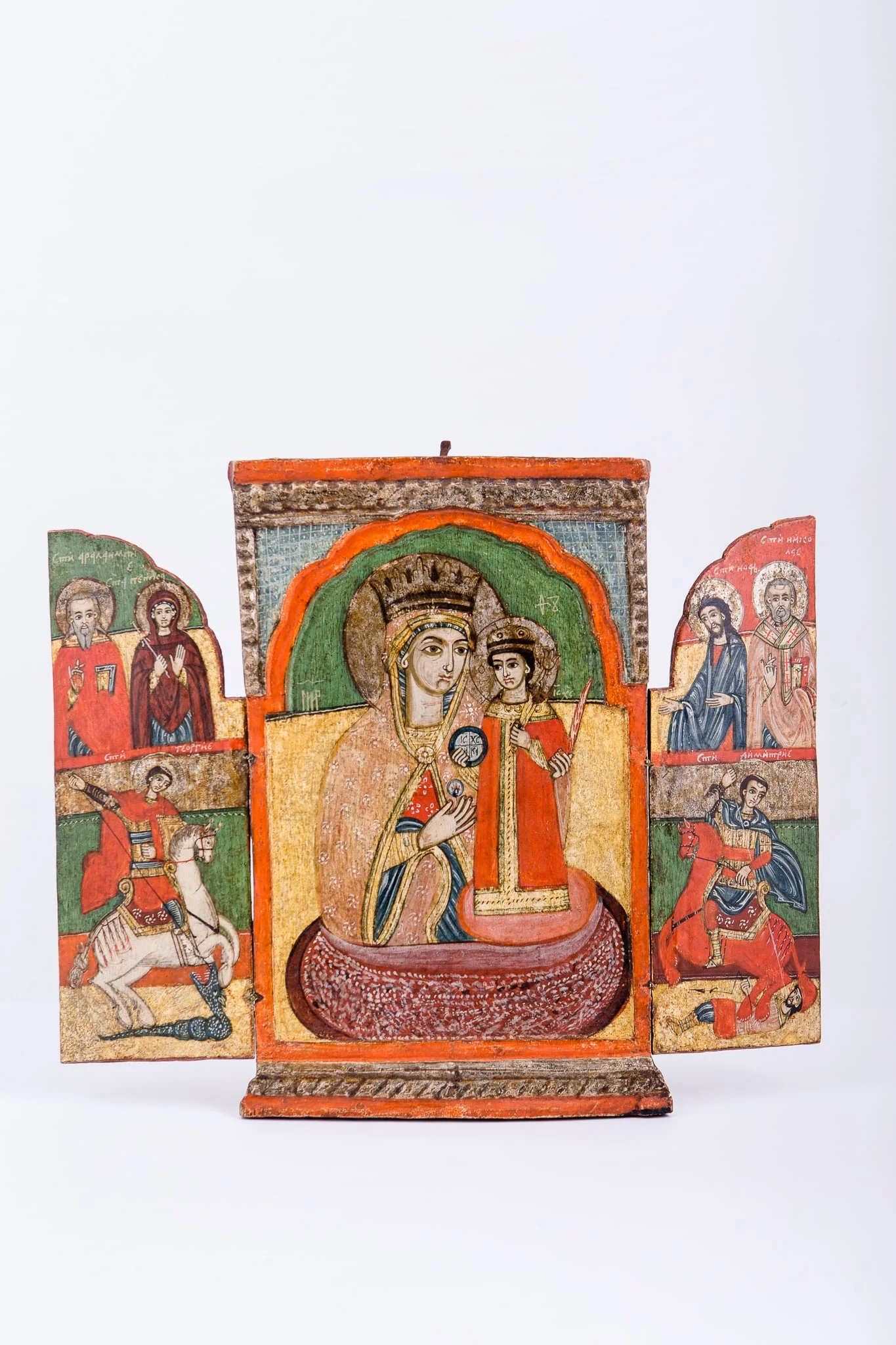 Icoana este un triptic - ansamblu de trei panouri pictate, unite prin conținut tematic iconografic comun și prin balamalele, prin care fețele laterale se închid de cea centrală. Tripticul este asemenea unei cărți sau ferestre, deschise-închise. Având stabilitate icoana centrală, tripticul poate avea valoarea de altar zburător. Tema centrală, care dă și titlul întregului ansamblu este Maica Domnului ține în brațe Pruncul Iisus Hristos, care Binecuvântează cu mâna dreaptă și ține globul pământesc cu crucea. Mântuitorul stă în picioare pe genunchii Maicii Domnului. Maica Domnului este înveșmântată în mantie cu maforion gălbui-crem-bej cu interiorul verde-roșu și ciupag auriu, are coroană și aureolă. Pruncul Iisus Hristos este înveșmântat în roșu sângeriu, cu bordură dantelată aurie, cu aureolă. Fondul icoanei este galben, în registrul inferior și verde în registrul superior. Icoana este încadrată de un chenar orange, portocaliu și un chenar crestat, basorelief, motivul funiei, de culoarea naturală a lemnului. În tematica fețelor laterale sunt reprezentați Sfântul Mare Mucenic Gheorghe purtător de biruință, Sfântul Mare Mucenic Dimitrie izvorâtor de mir, Sfânta Mare Cuvioasă Parascheva, Sfântul Ioan Botezătorul și doi sfinți ierarhi. Ușițe tripticului închizânduse, se realizează o imagine boltită, asemenea unor uși de biserică, pe care este inscripția în româno-chirilică: IC XC NIKA Iisus Hristos Biruiește! Cromatică: roșu vermillon, roșu-portocaliu, galben, verde, acajou, stacojiu, brun, bej,olive, auriu, negru. Inscripția pe icoana centrală, din româno-chirilică se traduce MP IC XC Maica Domnului Iisus Hristos., detail