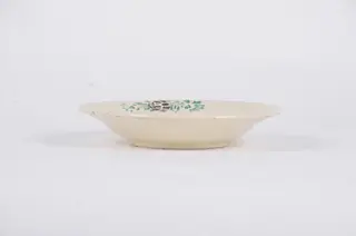 Farfuria este de formă tronconică fiind decorată cu motive florale dispuse central sub forma unui buchet de flori. Pe marginea piesei sunt dispuse într-un registru circular motive floral-vegetale pe un fond alb. Farfuria este smălțuită. Cromatică: fond: alb; motive: verde; maro., 1850