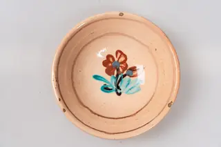 Farfurie adâncă, angobată pe fața interioară cu un strat de angobă albă. Este decorată prin pictare cu pensula și cu cornul cu motive florale, fitomorfe și geometrice: central pe fundul farfuriei este reprezentată o tulpină cu o floare și un boboc maro, cu centrul marcat de câte un punct gri, și frunze de culoare verde-turcoaz, încadrată într-un cerc de culoare maro. Buza este marcată de o linie circulară, de asemenea de culoare maro. Cromatica: alb, verde-turcoaz, maro, gri. Pe verso, farfuria are marca producătorului. Farfuria este acoperită pe ambele fețe cu un strat de smalț transparent., 1850