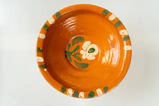 Farfurie adâncă, corpul de formă tronconică, cu buză îngustă, răsfrântă. Piesa este modelată la roata olarului, nefiind angobată. Decorul este realizat prin pictare cu pensula și constă în motive decorative florale (o floare cu frunze), dispuse central, pe fundul farfuriei și motive geometrice (linii groase, paralele), dispuse în trei registre, pe buza acesteia. Cromatica decorului: alb, verde. Farfuria este smălțuită pe interior, cu smalț transparent.