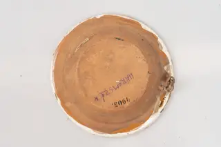 Farfurie adâncă cu buză îngustă, evazată și muchia buzei rotunjită, angobată pe suprafața interioară cu un strat de humă albă. Decorul este realizat prin pictare cu pensula și cu cornul și se compune din motive florale și geometrice, dispuse astfel: central pe fundul farfuriei, încadrat într-un cerc albastru, se găsește un buchet format din trei flori cu petale mici albastre și mijlocul din linii roșu-cărămiziu, și din doi boboci în culorile roșu-cărămiziu și albastru. Registrul marginal de pe buza farfuriei conține motive formate din câte două dungi scurte de culoare roșu-cărămiziu, între care sunt pictate grupuri de linii drepte hașurate intersectat, de culoare roșu-cărămiziu, albastru și verde. Decorul marginal este încadrat între două cercuri subțiri albastre. Suprafața ornamentată a farfuriei este acoperită cu un strat de smalț transparent. Cromatica: alb, albastru, roșu-cărămiziu, verde.
