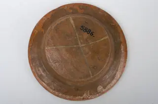 Farfurie adâncâ de formă tronconică cu marginea lată și rasfrântă oblic. Nu prezintă ornamente. Smălțuit numai în interior. Pe fund are un ”X” trasat cu cornul din angobă. Cromatică: fond brun; alb (”X”-ul de pe fund)., 1850
