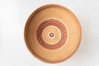 Farfurie adâncă de tip castron, cu bază îngustă și corp tronconic, buză mică dreaptă; piesa este modelată din lut la roata olarului nefiind angobată. Decorul foarte simplu este realizat cu albă și roșu-închis, prin pictare cu cornul și se compune din motive geometrice: linii circulare, linie ondulată, cercuri concentrice. Cromatica: alb, roșu-închis, pe fondul lutului ars. Farfuria este nesmălțuită., 1850