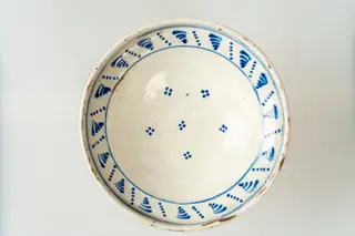 Farfurie adâncă, de tip castron. Piesă modelată la roata olarului, angobată cu alb pe fața interioară și decorată cu motive geometrice (grupuri și șiruri de puncte, grupuri de linii paralele, descrescătoare ca mărime, linii sub formă de cercuri concentrice), dispuse pe fundul farfuriei și pe buza acesteia. Farfuria este smălțuită pe fața interioară cu smalț transparent., 1850