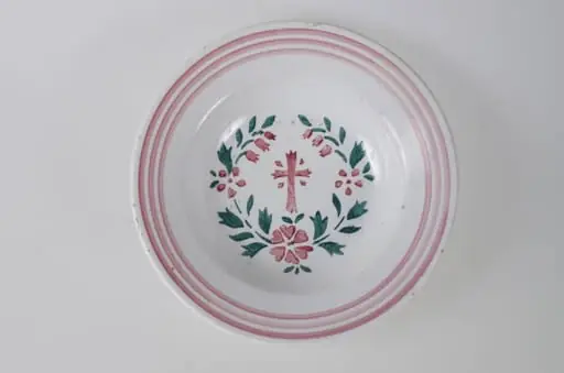 Farfurie de formă tronconică, adâncită; pe margine este decorată cu motive geometrice: trei cercuri concentrice. În centru este pictată o cruce, încadrată de flori și frunze dispuse circular. Pe exteriorul vasului de la bază spre buză se disting trei profile circulare. Cromatică: fond alb; motive: roșu; verde.