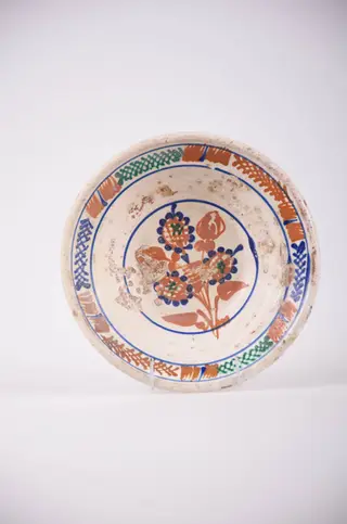 Farfurie de formă tronconică cu deschidere mare. Smălțuit în interior și ornamentat cu motive geometrice: cercuri; motive florale, pete de culoare și motiv vegetal: brăduț. Motivul floral se află pe fundul vasului și este înscris într-un cerc. Motivele vegetale și petele de culoare sunt amplasate pe marginea farfuriei și sunt încadrate de două cercuri. Cromatică: fond: alb; motive: maro; verde; albastru.