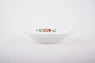 Farfurie de porțelan de formă tronconică, smălțuită în interior și la exterior. Pe fond alb avem flori stilizate (margarete). Buza farfuriei este conturată de o dungă neagră, iar pe margini sunt flori vișinii cu frunze verzi; în interiorul farfuriei pictate avem două flori mari (vișinii) și frunze verzi.