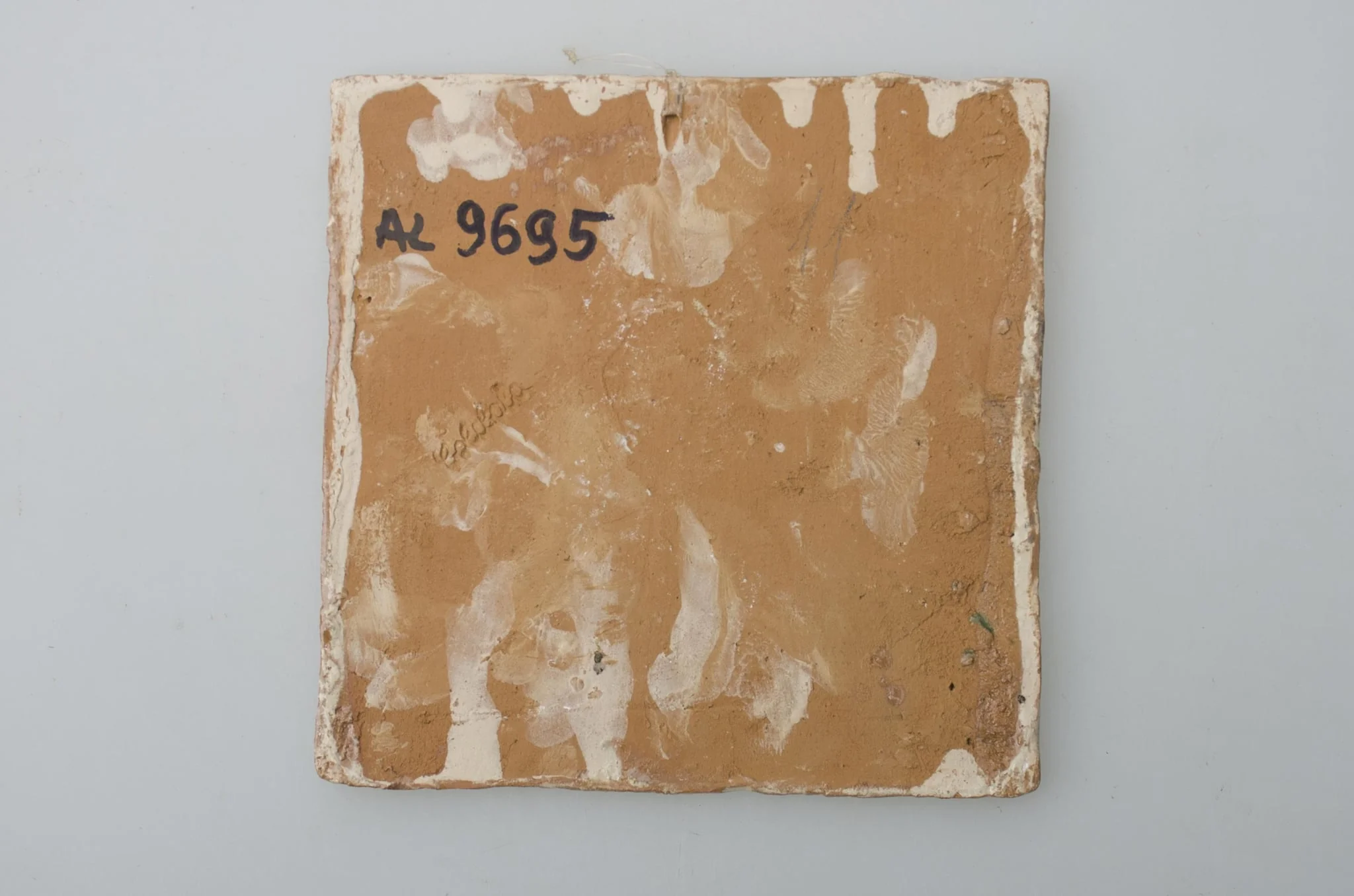 Piesă ceramică de formă pătrată, smălțuită și angobată, laturile pătratului fiind marcate de două chenare, primul vălurit, al doilea în linie dreaptă. Ornamentată cu motive zoomorfe și floral-vegetale, după fabula lui La Fontaine, Vulpea și barza: o vulpe care bea dintr-un ulcior și o barză care mânâncă dintr-un vas plat aflat pe o măsuță joasă. Pe două din colțuri, două flori completează pictura. Motivele au fost la început incizate, iar apoi pictate. Pe spate, cahla este prevăzută cu un orificiu pentru prinderea aței. Tot aici, este inscripționat numele meșterului olar, "Colibaba". Cromatică: fundal alb; motive: verde, galben, maro, cărămiziu., detail