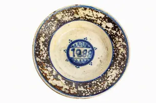 Formă tronconică; fond alb. Decorul, pictat pe fond alb și amplasat în centrul farfuriei, este reprezentat de un cerc albastru în care se află data : 1888 încadrată sus și jos de două valuri albastre. Pe umărul vasului este amplasată o bandă circulară lată de culoare brună, cu smalțul sărit în mai multe locuri dînd senzația că a fost decorată prin stropire cu pensula. Folosită la decorarea interiorului țărănesc în așa numita - cameră bună.