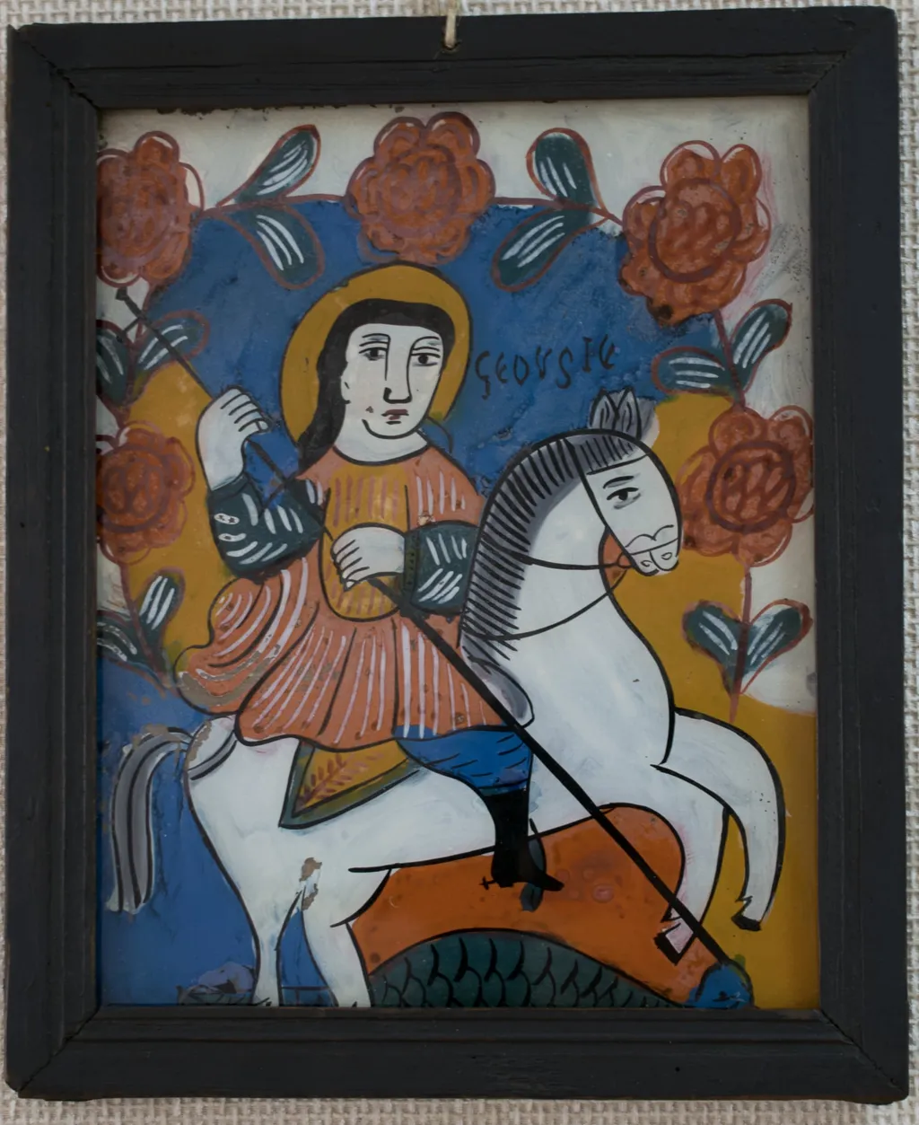 Icoana este pictată "în oglindă", pe un suport de sticlă de formă dreptunghiulară în ax vertical. Tema iconografică: Sfântul Gheorghe omorând balaurul. Sfântul, călare pe cal alb, este plasat în centrul icoanei. Veșminte ostășești, cizme înalte, tunică scurtă, roșie, cu mâneci verzi, pantaloni albaștri, bufanți.Capul descoperit, părul lung, negru, revărsat pe umeri. Aureola trasată cu mâna liberă. În mână ține o suliță lungă pe care o înfige în gura balaurului reptilian, verde, simbolizând zonele inferioare, ale păcatului. În jumătaea superioară o ghirlandă de trandafiri dispusă în arcadă deasupra sfântului. Icoana are caracteristici specifice picturii niculene: stângăcia, simplitatea și primitivismul desenului; compoziția sumară,este mai încărcată totuși decât la icoanele niculene din prima perioadă. Paleta cromatică sobră, culorile intense:alb, orange, roșu, verde, albastru, negru. Rama profilată, de culoare neagră, dosul din scândură subțire de brad., by Hugo Kołłątaj