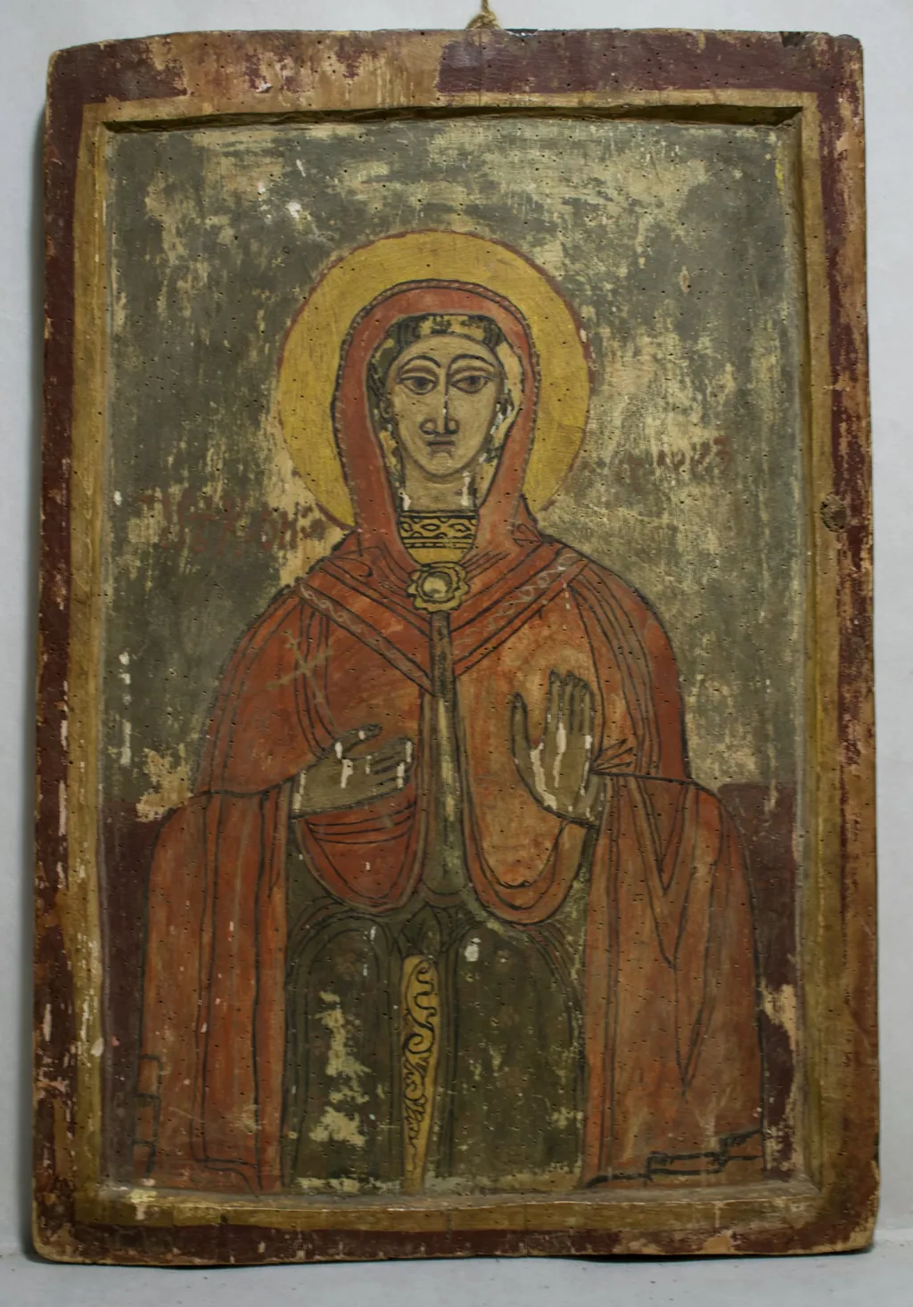 Sfânta Cuvioasă Paraschiva este redată 3/4, frontal, într.o manieră naivă, specific țărănească. Chip oval, trăsăturile feței accentuate, ochii conturați cu negru, privirea îndreptată lateral, scrâncenele mult arcuite, nările mari, gura mică. Mâna stângă o ține la piept, dreapta ridicată în semnde binecuvântare. Înveșmântată cu un maforion roșu pal, cu decorațiuni vagi, albe, stola verde cu galben, porțiune decorată cu motive fitomorfe.Nimb galben cu linia de contur albă. Fond grena în partea de jos, gri în cea superioară. Chenar dublu, galben + grena., by Hugo Kołłątaj