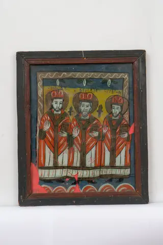 Icoana îi reprezintă pe cei trei sfinți ierarhi, Vasile cel Mare, Grigorie Teologul și Ioan Gură de Aur, pictați frontal, în picioare. Cei trei sfinți binecuvântează cu dreapta, iar în stânga țin Evanghelia. Sfinții sunt îmbrăcați în veșminte arhierești și cu mitre pe cap. Fizionomiile sunt asemănătoare, doar sfântul Vasile, pictat la mijloc, are barba mai lungă decât ceilalți doi sfinți. Compoziția e delimitată în partea superioară de un brâu ornat cu motivul torsadei. Cromatica icoanei se compune din tonuri de roșu vermillon, ocru galben, alb, verde, albastru, negru și gri. Rama icoanei e profilată, bicromă și e formată din îmbinarea a patru baghete de lemn. Sticla e spartă în mai multe fragmente, iar din partea inferioară lipsesc trei fragmente de mici dimensiuni.